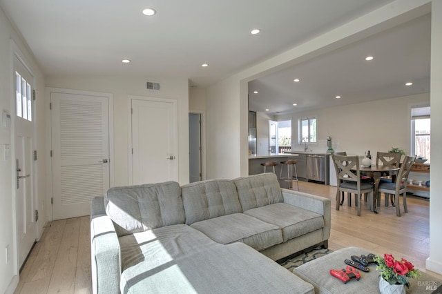 living room with lofted ceiling, sink, and light hardwood / wood-style floors