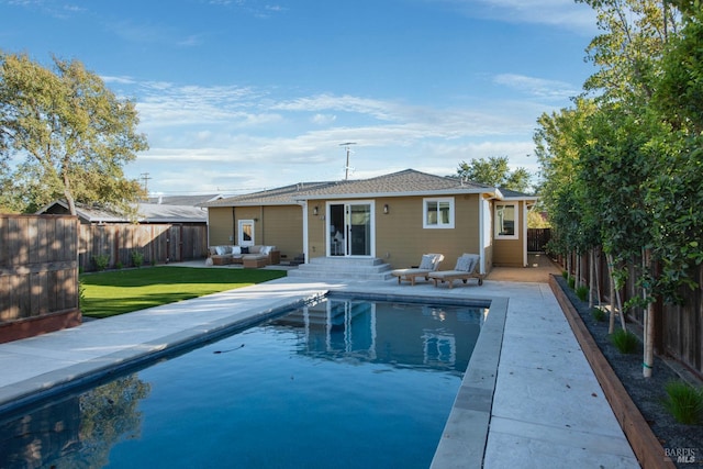 rear view of house featuring outdoor lounge area, a lawn, and a fenced in pool