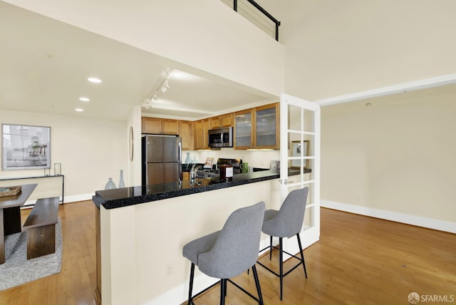 kitchen featuring sink, light hardwood / wood-style flooring, appliances with stainless steel finishes, a kitchen bar, and kitchen peninsula