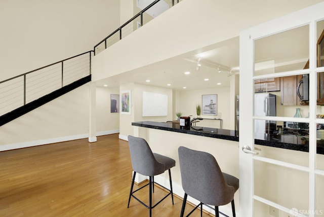 kitchen with a kitchen bar, hardwood / wood-style floors, and fridge