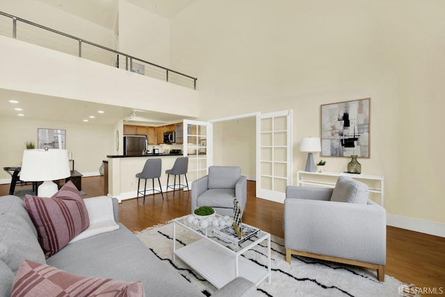 living room with french doors, a high ceiling, and hardwood / wood-style flooring