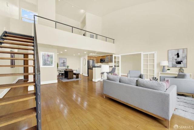 living room featuring french doors, wood-type flooring, and a high ceiling