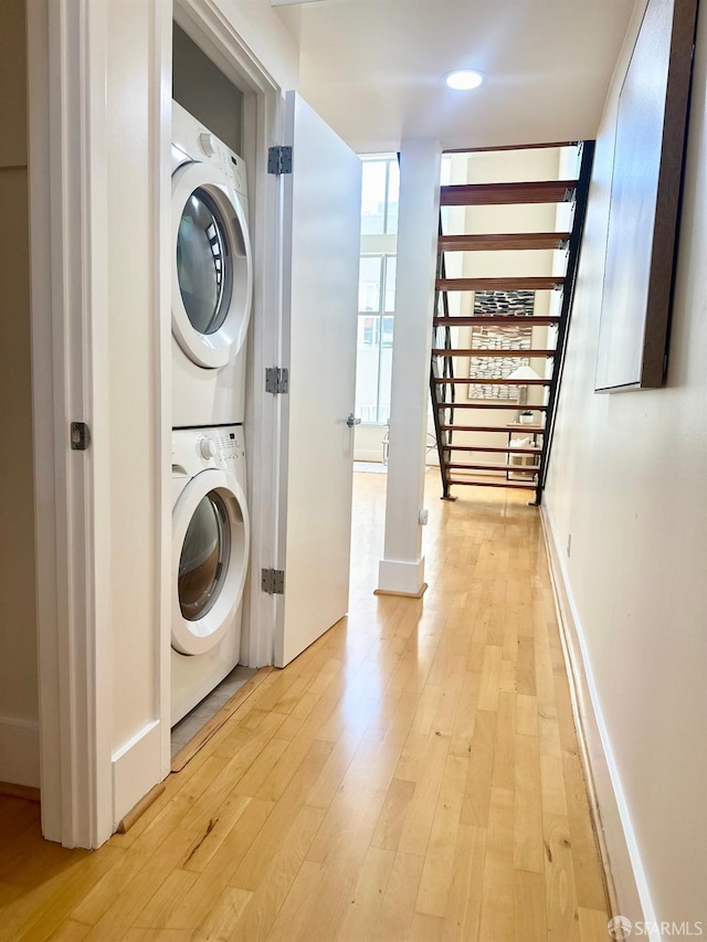 clothes washing area featuring light hardwood / wood-style flooring and stacked washer / drying machine