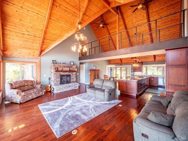 living room featuring ceiling fan with notable chandelier, dark hardwood / wood-style flooring, high vaulted ceiling, beam ceiling, and a fireplace