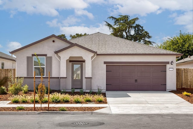 view of front facade with stucco siding, fence, roof with shingles, concrete driveway, and a garage