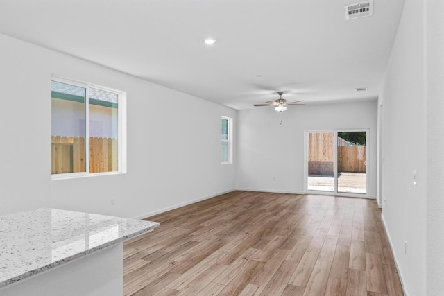 unfurnished room featuring a ceiling fan, light wood-style floors, visible vents, and a wealth of natural light