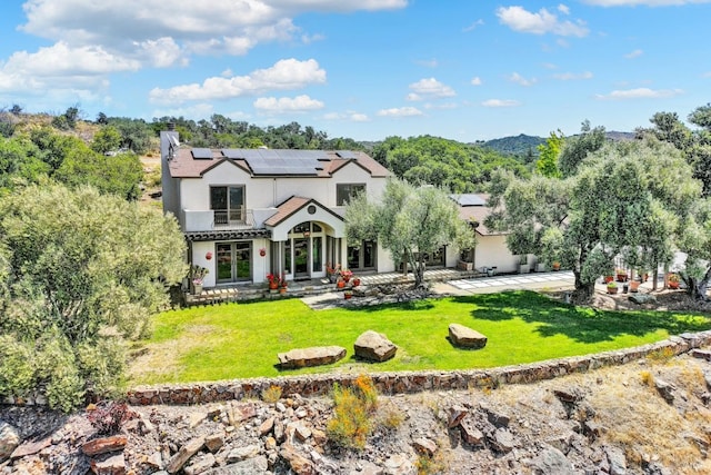 view of front of house with a front yard, solar panels, and a patio area