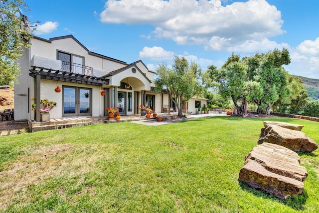 back of house with a lawn, a balcony, and french doors