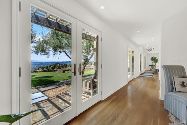 entryway featuring french doors, wood-type flooring, and a notable chandelier