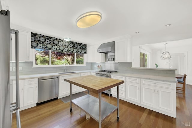 kitchen with stainless steel appliances, light wood-type flooring, white cabinetry, decorative light fixtures, and sink