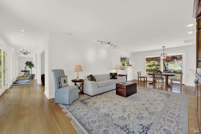 living room featuring track lighting, wood-type flooring, and a chandelier