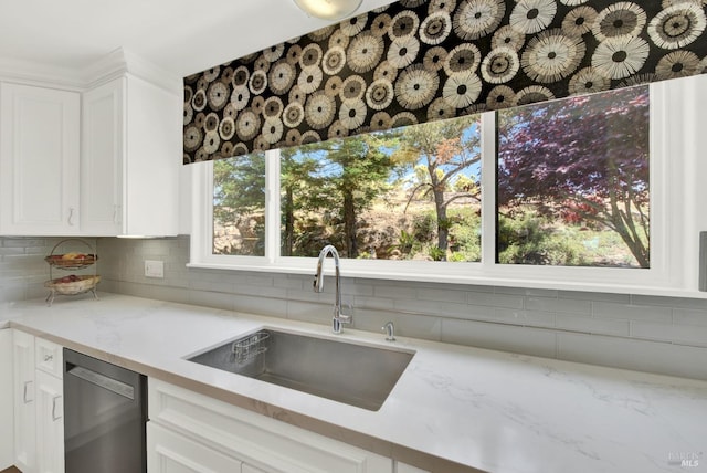 kitchen featuring light stone counters, backsplash, sink, white cabinets, and stainless steel dishwasher