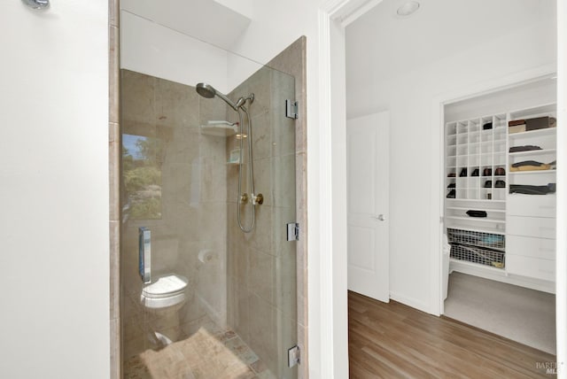 bathroom featuring toilet, an enclosed shower, and hardwood / wood-style flooring