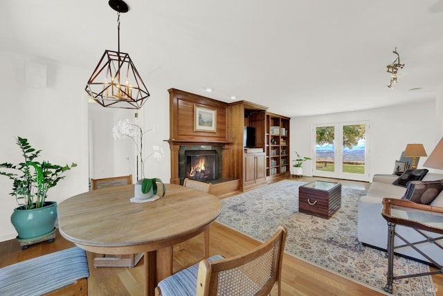 living room with light wood-type flooring, a chandelier, and a fireplace