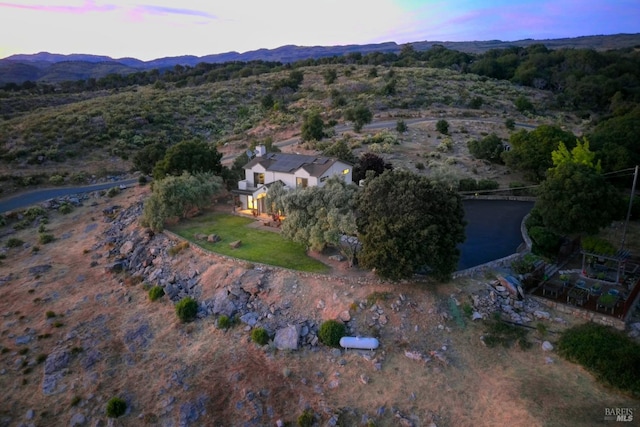 aerial view at dusk featuring a water and mountain view