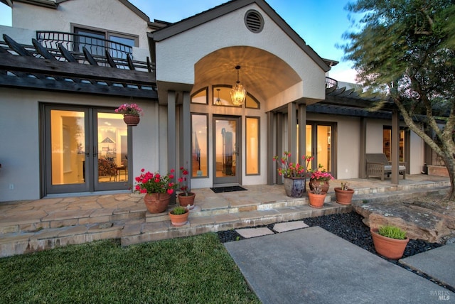 view of exterior entry featuring a patio and a balcony