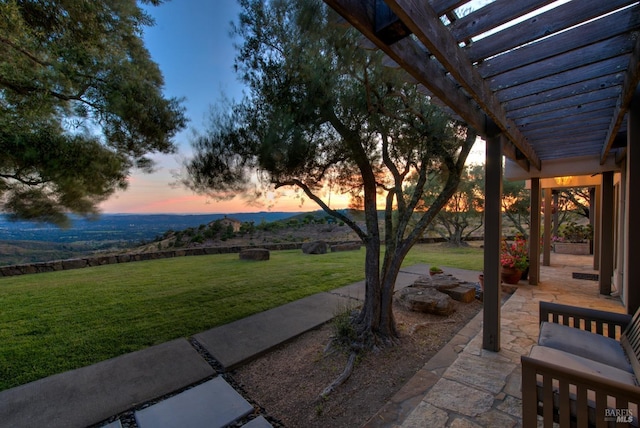 patio terrace at dusk featuring a yard and a pergola