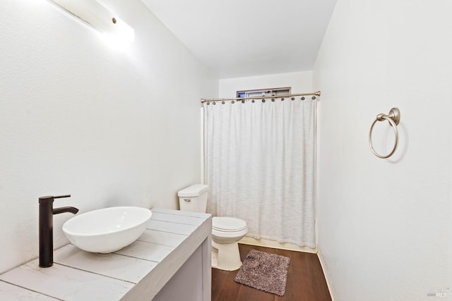 bathroom featuring curtained shower, toilet, a sink, wood finished floors, and baseboards