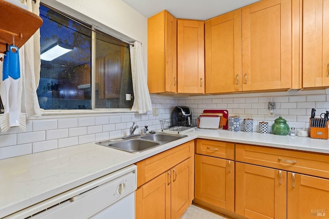 kitchen featuring white dishwasher, sink, and tasteful backsplash