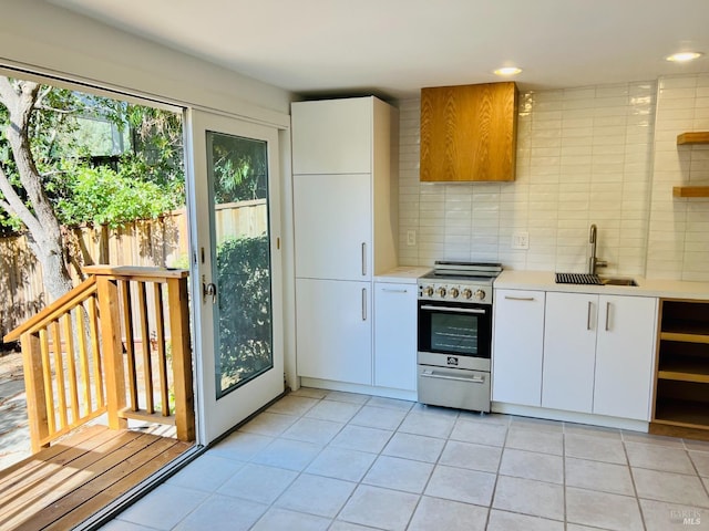 kitchen with sink, tasteful backsplash, stainless steel range with electric cooktop, light tile patterned floors, and white cabinetry