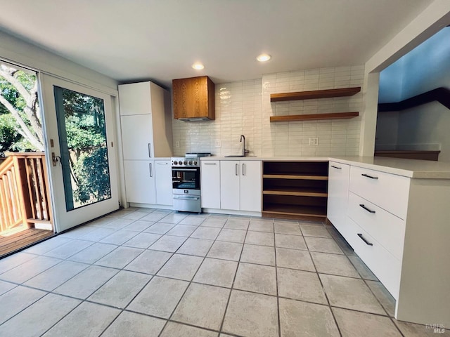 kitchen with sink, tasteful backsplash, light tile patterned floors, white cabinets, and electric stove