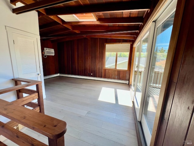 spare room featuring baseboard heating, lofted ceiling with beams, light hardwood / wood-style floors, and wood walls