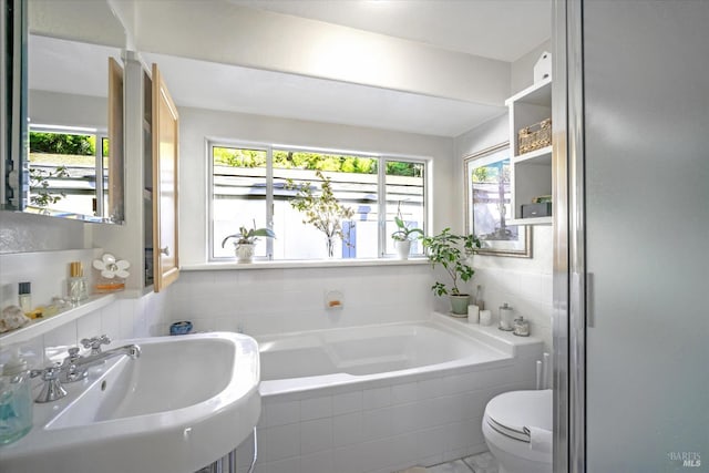 bathroom featuring toilet, sink, and tiled tub