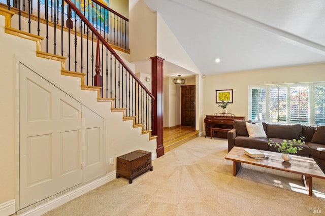 carpeted living room featuring beamed ceiling, decorative columns, and high vaulted ceiling