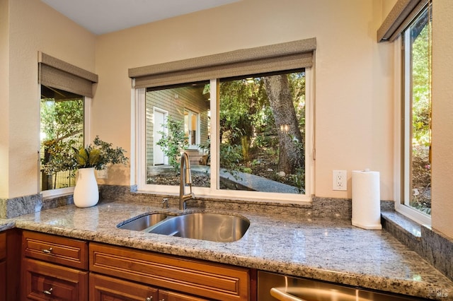 kitchen featuring a wealth of natural light, sink, and light stone countertops