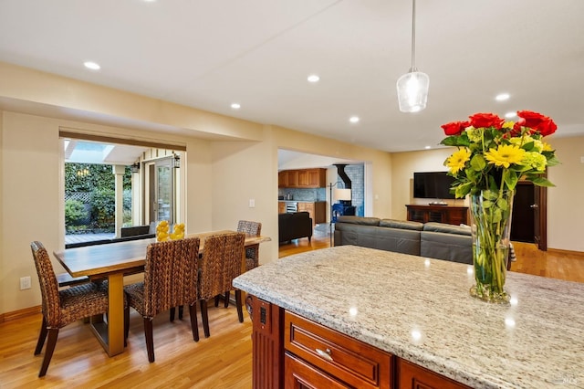 kitchen featuring pendant lighting, light hardwood / wood-style floors, and light stone counters