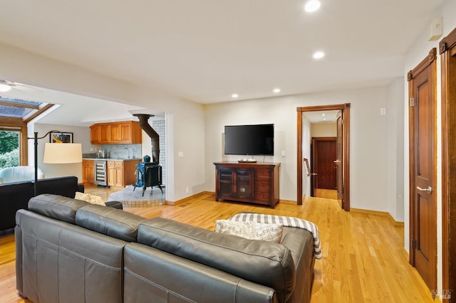 living room with wine cooler, ceiling fan, and light hardwood / wood-style flooring