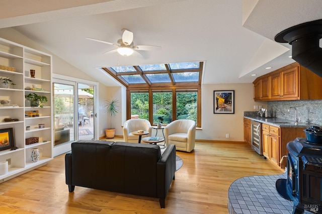 living room with light hardwood / wood-style floors, beverage cooler, a wood stove, and a wealth of natural light