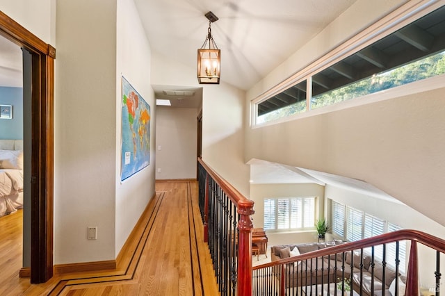 corridor with hardwood / wood-style flooring, an inviting chandelier, and lofted ceiling