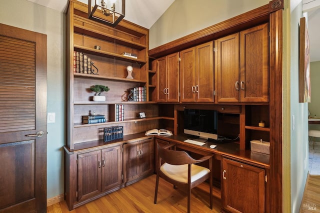 office area with built in desk, lofted ceiling, and light hardwood / wood-style flooring