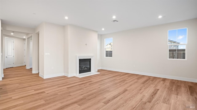 unfurnished living room featuring plenty of natural light and light wood-type flooring