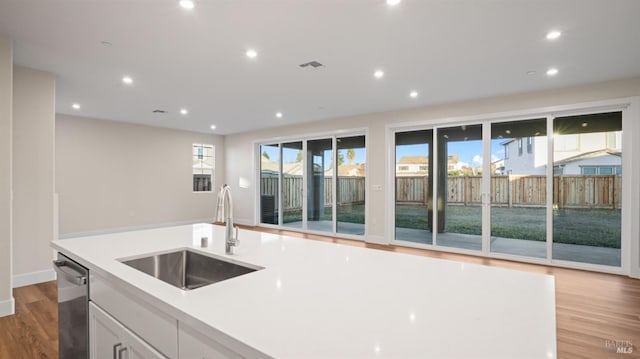 kitchen featuring sink, light hardwood / wood-style flooring, dishwasher, a healthy amount of sunlight, and white cabinets