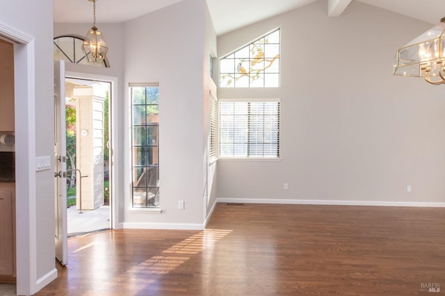 foyer entrance with high vaulted ceiling, dark hardwood / wood-style flooring, and a notable chandelier