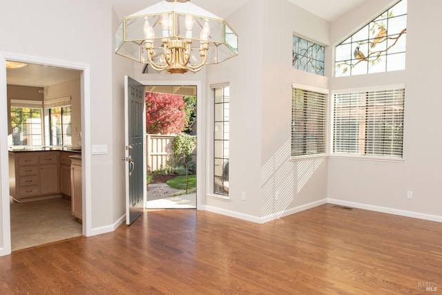 entrance foyer with a towering ceiling, dark hardwood / wood-style floors, and a chandelier