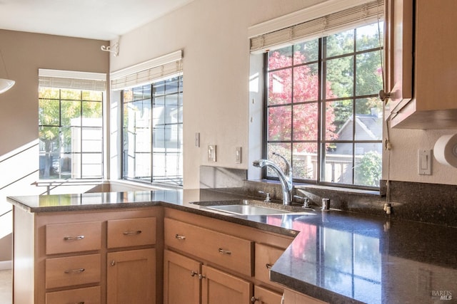 kitchen featuring dark stone counters, sink, and kitchen peninsula