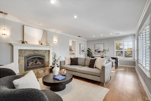 living room with hardwood / wood-style floors, a tile fireplace, crown molding, and visible vents