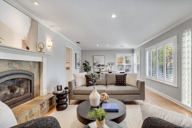 living area featuring wood finished floors, ornamental molding, a textured ceiling, and a tile fireplace