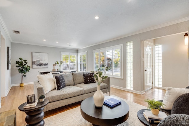 living room with a textured ceiling, light wood-style flooring, visible vents, and crown molding