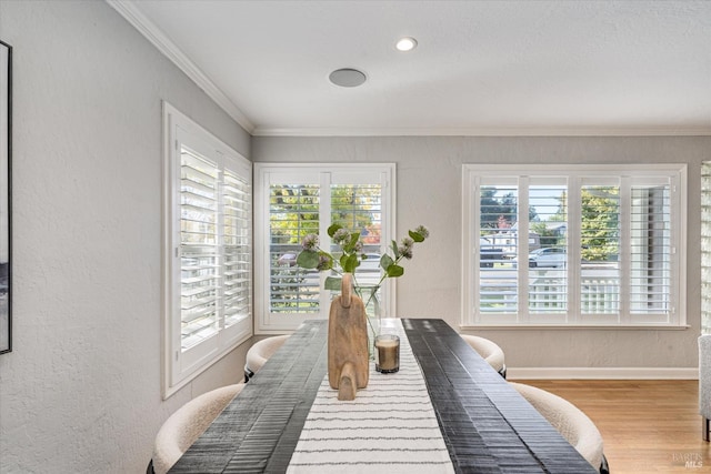 interior space with light wood-style floors, a textured wall, multiple windows, and crown molding