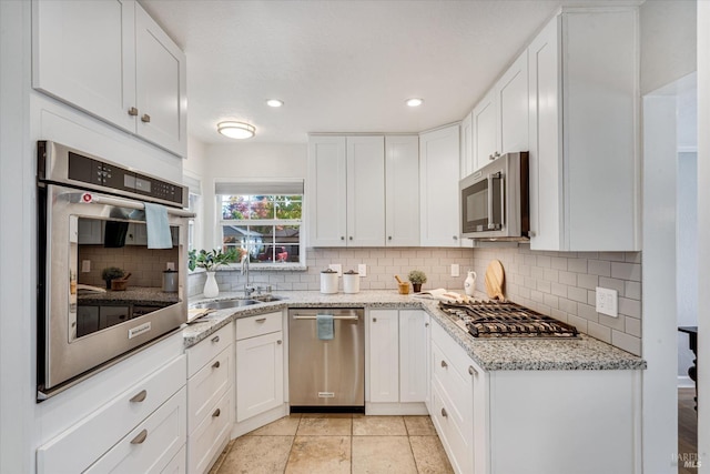 kitchen with white cabinetry, decorative backsplash, a sink, and stainless steel appliances