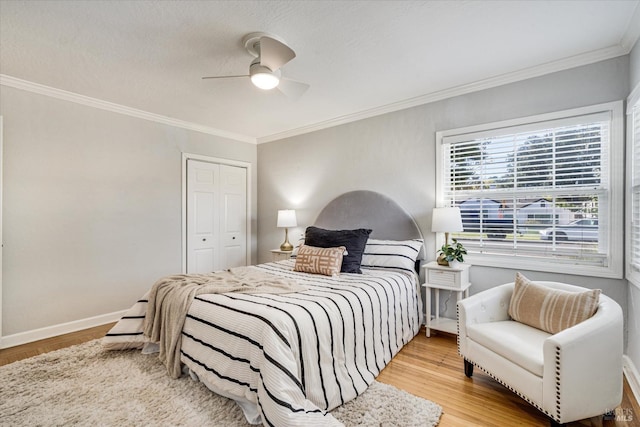 bedroom with ornamental molding, baseboards, a ceiling fan, a closet, and wood finished floors