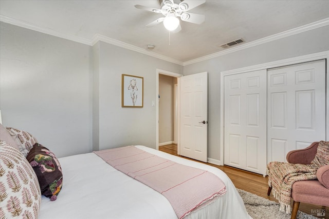 bedroom featuring crown molding, visible vents, a ceiling fan, a closet, and wood finished floors