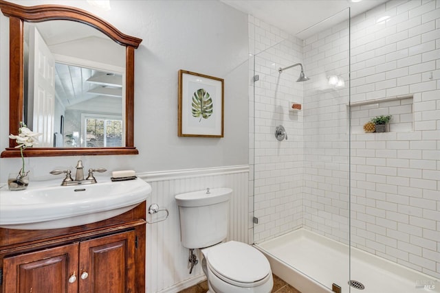 bathroom with vanity, a wainscoted wall, toilet, and tiled shower