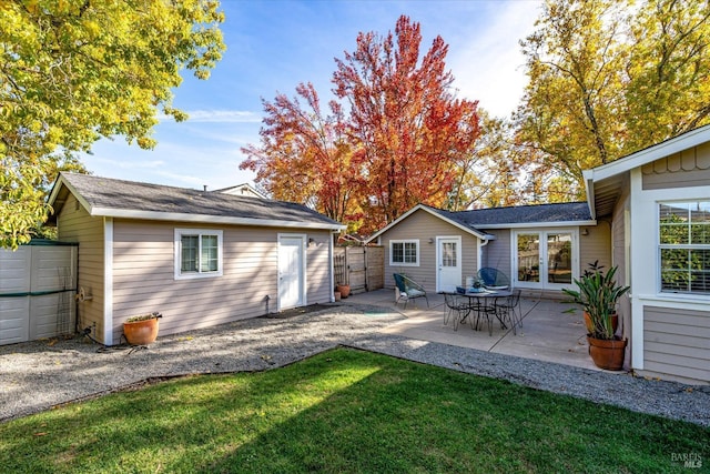 rear view of house with a patio area, french doors, fence, an outdoor structure, and a yard