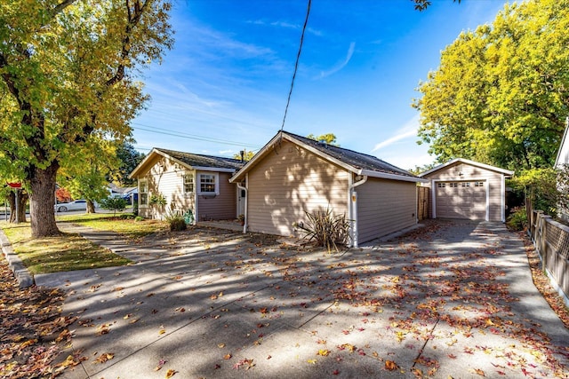 view of property exterior featuring an outbuilding, driveway, fence, and a detached garage