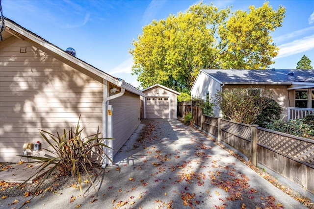 view of home's exterior featuring an outdoor structure, driveway, and fence